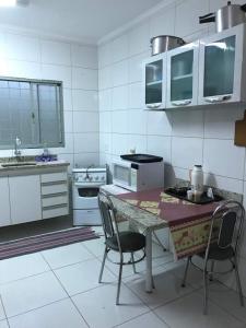 eine weiße Küche mit einem Tisch und 2 Stühlen in der Unterkunft Casa - Chácara Bella Arraes in Bauru
