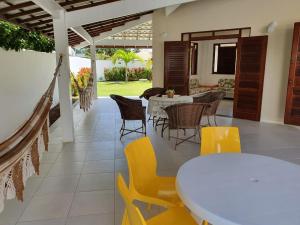 un patio con una mesa blanca y sillas en Guarajuba - casa em condomínio corais a 200 metros da praia, en Camaçari