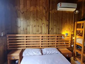a bedroom with a bed and a wooden wall at Cantinho do paraíso in Gamboa
