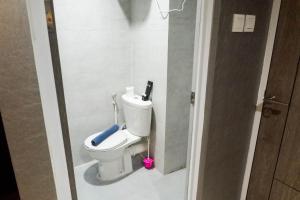 a bathroom with a toilet with a blue mop at Modern Spacious Studio Room Apartment at Taman Melati Surabaya By Travelio in Surabaya +5 photos