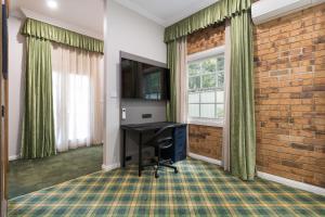 Habitación con escritorio y pared de ladrillo. en The Carrington Inn - Bungendore en Bungendore