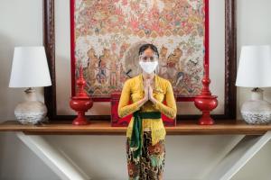 a woman wearing a mask praying in front of a painting at Bali Paragon Resort Hotel in Jimbaran