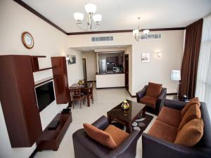 a living room with a couch and chairs and a television at Xclusive Maples Hotel Apartment in Dubai