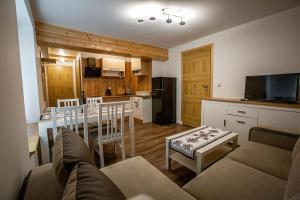 sala de estar con sofá, mesa y cocina en Apartamenty przy skoczni, en Szczyrk