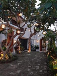 une cour d'une maison ornée d'arbres et de lumières dans l'établissement La Rose Villas and Suites Camp Canggu, à Canggu