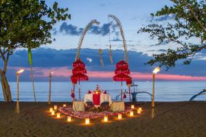 a table with candles on a beach with the ocean at Bali Taman Lovina Resort & Spa Suites in Lovina