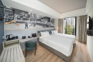 a room with a bed, a desk and a painting on the wall at Travelodge Bukit Bintang in Kuala Lumpur