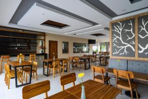 een restaurant met houten tafels en stoelen en een grote muur bij The Calna Villa Bali in Kuta