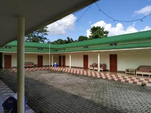 ein Gebäude mit einem grünen Dach und Bänken im Innenhof in der Unterkunft Bagori Resort-Best Holiday Resort in Kaziranga in Sakmuthi