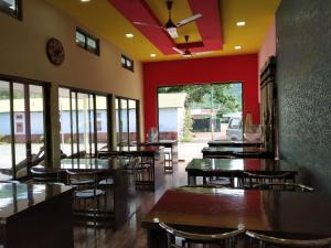 ein Restaurant mit Tischen, Stühlen und roten Wänden in der Unterkunft Bagori Resort-Best Holiday Resort in Kaziranga in Sakmuthi