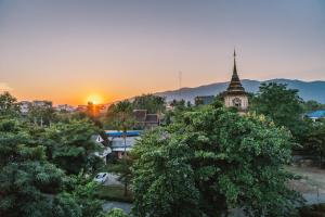 a sunset over a city with a church and trees at B Innspire Hotel in Chiang Mai