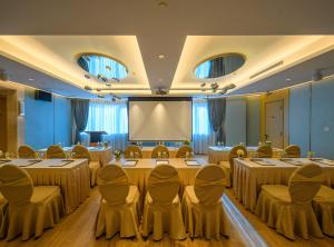 una sala de conferencias con mesas y sillas y una pantalla de proyección en Grand Dragon Hotel en Macao