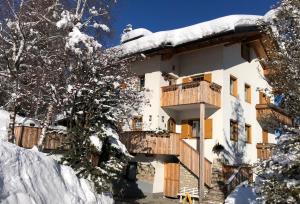 Un edificio cubierto de nieve con un balcón con árboles cubiertos de nieve. en Apartments Ciasa Colz, en La Villa