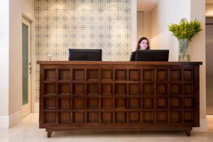 a woman sitting at a reception desk with two laptops at Arthur Hotel - an Atlas Boutique Hotel in Jerusalem