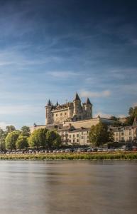 a large castle on top of a building next to a river at Appartement 1-6 pers situé entre les ponts in Saumur