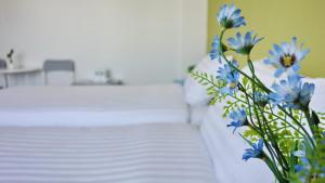 a vase filled with blue flowers next to a bed at Kata Bai D - SHA Certificate Hotel in Kata Beach