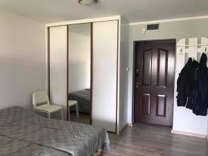 a bedroom with a bed and a door with a mirror at Apartament Leśna Jarosławiec in Jarosławiec