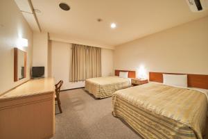 a hotel room with two beds and a television at Hotel First Stay Amagasaki in Amagasaki