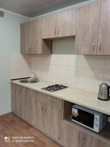 eine Küche mit Holzschränken, einer Spüle und einer Mikrowelle in der Unterkunft 35 проспект Миру in Krywyj Rih