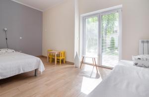 a white room with two beds and a window at Apartament pod Żaglem z Widokiem na Jezioro, Oczy Mazur in Giżycko