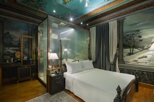 um quarto com uma grande cama branca num quarto com pinturas em Trésor Art Boutique Hotel em Korçë