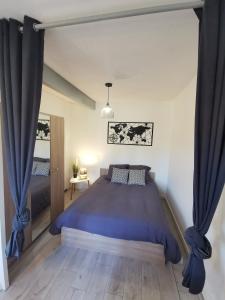 Schlafzimmer mit einem großen Bett und blauen Vorhängen in der Unterkunft Studio COSY Tout Confort Proche Hyper-Centre in Cognac