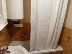 a bathroom with a white shower curtain next to a sink at Apartman Kneginja in Trstenik