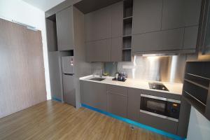 a kitchen with gray cabinets and a wooden floor at Ceylonz Seasonal Suites in Kuala Lumpur
