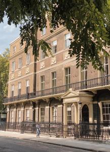 a woman walking in front of a large brick building at Home House - Private Member's Club in London