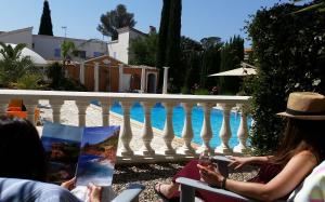 - un groupe de personnes assises sur une terrasse couverte à côté d'une piscine dans l'établissement Chambre d'hôtes La Potinière, à Saint-Raphaël