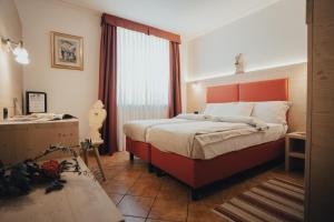 una camera con un grande letto con testiera arancione di Hotel Bezzi a Passo del Tonale