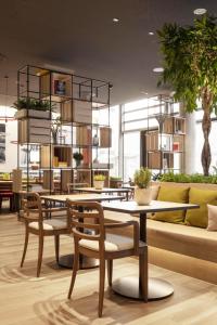- un restaurant avec des tables, des chaises et un canapé dans l'établissement IntercityHotel Hildesheim, à Hildesheim