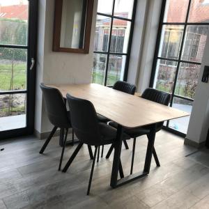 a wooden table and chairs in a room with windows at D'n Wasschappelsen Engel Windkracht 11 in Westkapelle