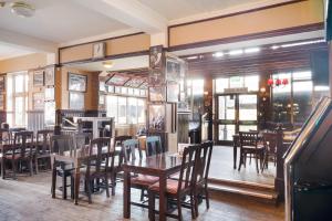um restaurante com mesas e cadeiras de madeira e janelas em OYO The Green Man Pub And Hotel em Londres