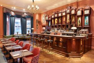 um restaurante com um bar e mesas e cadeiras em Home House - Private Member's Club em Londres