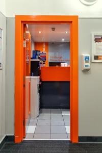 an orange door in an office with a counter at easyHotel Edinburgh in Edinburgh