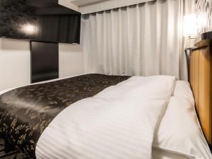 a bedroom with a bed with a black and white blanket at APA Hotel SHIN-OSAKA MINAMIKATA EKIMAE in Osaka