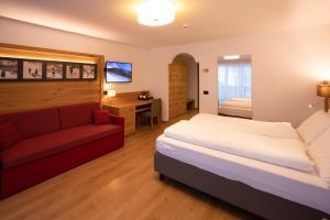 Habitación de hotel con cama y sofá rojo en Residence Meridiana, en Andalo