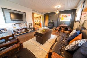 a living room with a leather couch and a television at Luomajärven Hevoskievari in Karhoinen