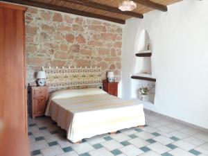 a bedroom with a bed and a stone wall at Sa Perda Arrubia in Cardedu