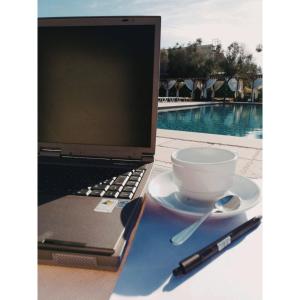 Masseria Stali, The Originals Relais في Caprarica di Lecce: جهاز كمبيوتر محمول يجلس على طاولة مع كوب من القهوة