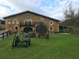 un edificio in pietra con un grande orologio nel cortile di MendiGoikoa Bekoa a Axpe