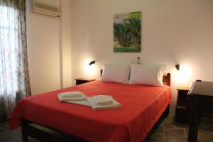 a bedroom with a red bed with two towels on it at Voula's Casa Di Mare in Palekastron