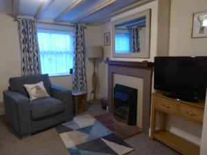 sala de estar con chimenea, silla y TV en Herriot's Nook, en Thirsk