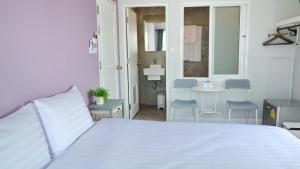 a bedroom with a white bed and a table and chairs at Kata Bai D - SHA Certificate Hotel in Kata Beach