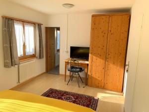 a bedroom with a bed and a desk with a television at Waldheim Pension Laax in Laax