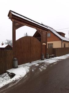 uma cerca de madeira com um portão em frente a uma casa em Emília vendégház em Ciumani