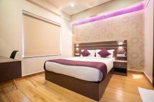 a bedroom with a large bed with purple lighting at Lavender Infopark Kochi in Kakkanad