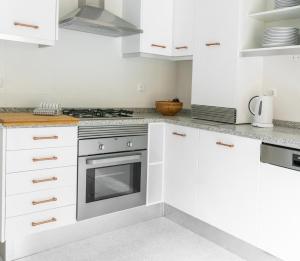 a kitchen with white cabinets and a stove at Casa amigavel do Mar in Sesimbra