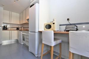 Il comprend une cuisine équipée d'un réfrigérateur blanc et d'un comptoir avec des chaises. dans l'établissement Estepona Port Apartment FLO, à Estepona